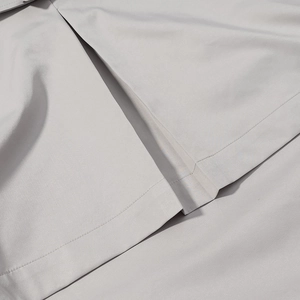 Detailed close-up of light gray trench coat hem showing fine stitching and smooth fabric