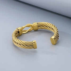 Detail of golden stainless steel braided cable bracelet with central metal buckle knot