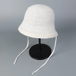 Detail of breathable knit bucket hat showing soft cream texture and woven tie-straps