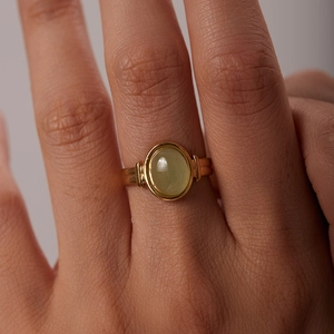 Bague ovale en or 18 carats avec pierre semi-précieuse vert clair sur la main