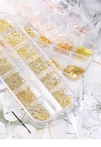 Macro view of assorted gold and silver alloy nail art studs and shapes in 12-slot storage box