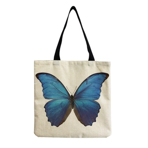 Tragetasche aus cremeweißem Canvas mit großem blauen Schmetterlingsdruck und schwarzen Trägern
