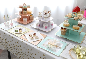Detailed close-up of three-tier pastel cake stands and disposable gold-rimmed party plates