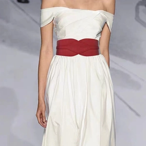 Close-up of a stylish wide red leather waist belt paired with an elegant white dress