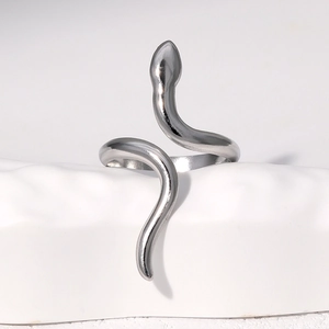 Détail d'une bague serpent en argent poli sur un présentoir géométrique blanc