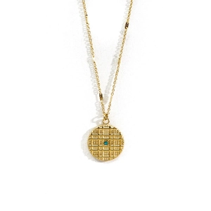 Detail of 14K gold plated circular pendant with grid texture and blue gemstone