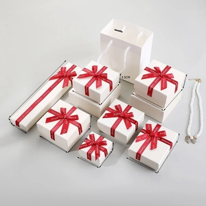 White jewelry gift boxes with red ribbons and matching paper bags in various sizes