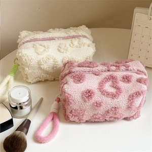 Macro shot of fluffy cream and pink cosmetic bags with soft 3D floral patterns