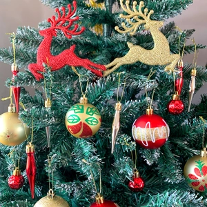 Dettaglio di palline di Natale rosse e oro, renne glitterate e ghiaccioli sull'albero