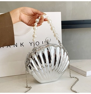 Detail of silver shell clutch bag with large pearl handle and metal chain strap