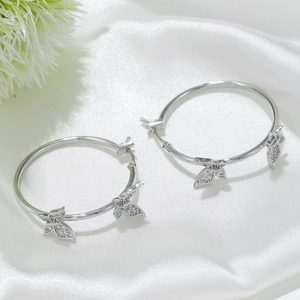 Créoles en argent avec pendentifs papillon sertis de zircons sur fond de soie blanche