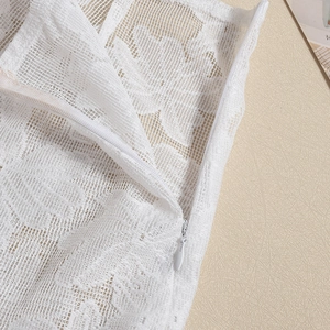 Detailed close-up of white floral lace fabric and matching invisible zipper on the garment