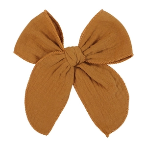 Detailed close-up of a mustard yellow bow hair clip with textured cotton linen fabric