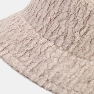 Close-up of thick beige plush teddy fabric texture on a warm winter bucket hat