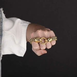 Detailed close-up of a gold-tone punk skull bracelet on a wrist with heavy metal links