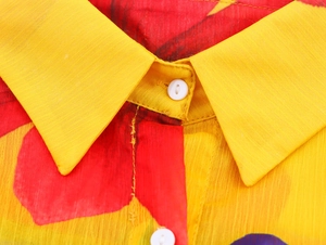 Detailed macro view of floral chiffon shirt collar and buttons with vibrant prints