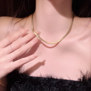Elegant gold flat snake chain necklace made of stainless steel on a black background