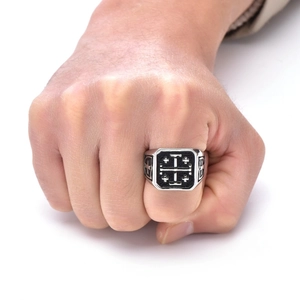 Macro shot of a men's vintage silver titanium cross ring with detailed black patterns