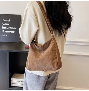Detailed texture of brown corduroy shoulder bag shown on model in a minimalist home setting