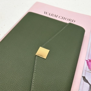 Close-up of dark green lychee texture leather with a square gold metal buckle