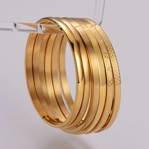 Minimalist gold bangle set with roman numerals and textured finishes on display