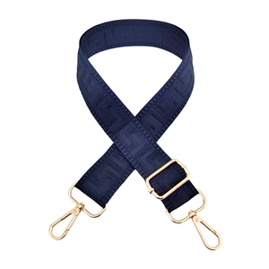 Detail of navy blue wide bag strap with geometric maze pattern and gold lobster clasps
