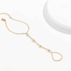 Detail of gold finger bracelet featuring delicate metal chains and sparkling crystals
