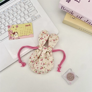 Macro detail of floral bunny ear drawstring storage bag on a cozy minimalist desk