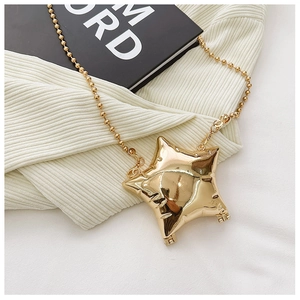 Macro detail of glossy gold star mini bag with metallic texture and beaded chain strap