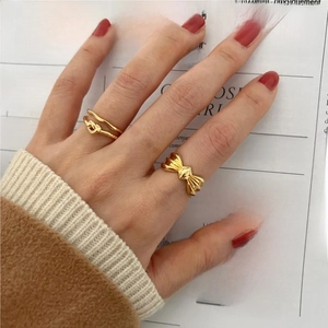925 Sterling silver bow and knot gold ring set displayed on hand over a magazine background