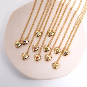 Close-up of heart locket necklaces with various colored birthstones on a stone tray