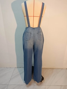 Back view of loose fit denim jumpsuit featuring large rear pockets and adjustable straps