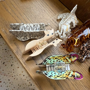 Assorted leopard print and animal-shaped hair claws displayed on a rustic wooden table