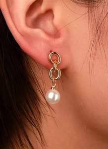 Detail of triple gold rings stud earring with round white pearl drop on female ear