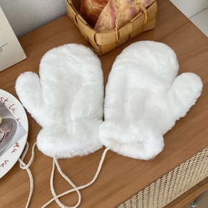 Detail of white plush mittens with a woven anti-lost lanyard on a wooden tabletop