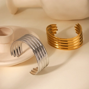 Detail of multilayer wave bangles in gold and silver finish on ceramic display