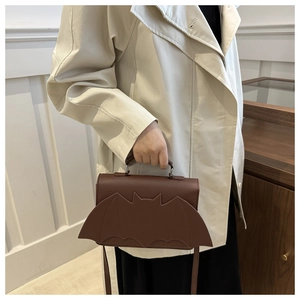 Detail of brown bat-shaped leather handbag with handle and crossbody strap