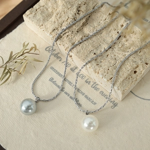 Elegant silver chain necklace featuring white and grey pearl pendants on stone decor
