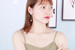 Close-up of model wearing silver LOVE letter pendant necklace and pearl tassel earrings