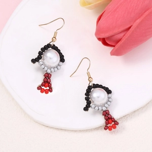 Close-up of handmade beaded earrings with white pearls and gold hooks on ceramic plate