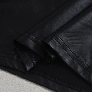 Détail macro de la texture du cuir noir et des coutures de précision sur l'ourlet