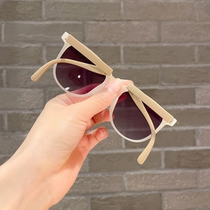 Detail showing foldable cream children's sunglasses with CE mark and dark lenses