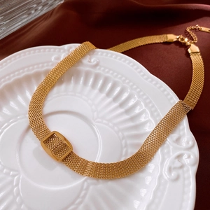 Detailed close-up of golden mesh necklace set displayed on an elegant relief white plate