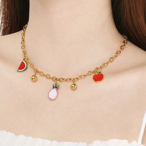 Collier d'été en acier titane doré avec breloques de fruits en émail portées par modèle
