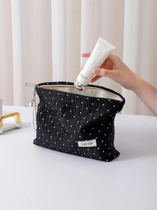 Black polka dot travel toiletry bag with textured fabric and pearl charm accessory