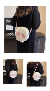 Detail view of a creative skull-shaped crossbody bag with pink eyes and silver zipper