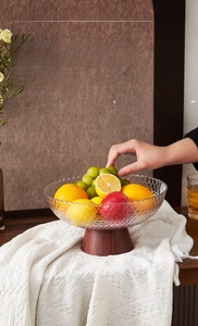 Close-up of vintage style fruit bowl with textured glass and wood grain base on table