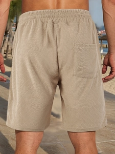 Rear view of men's beige shorts showing geometric jacquard texture and elastic waistband