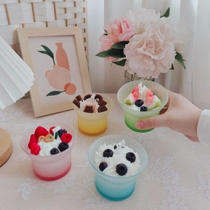Detailed view of scented dessert candles with cream topping and berries in frosted glass