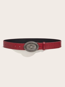 Detail of red crocodile pattern leather belt with silver oval sunburst buckle